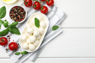 Tasty mozzarella cheese, tomatoes, basil and spices on white wooden table, flat lay. Space for text