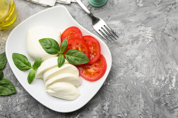 Tasty mozzarella cheese, tomato, basil and spices on grey table, flat lay. Space for text