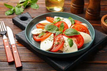 Tasty salad Caprese served on wooden table, closeup