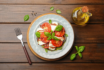 Tasty salad Caprese served with balsamic vinegar on wooden table, flat lay