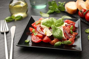 Tasty salad Caprese served on black table, closeup
