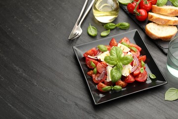 Tasty salad Caprese served on black table, above view. Space for text