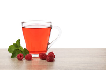 Tasty raspberry tea, berries and leaves on wooden table against white background