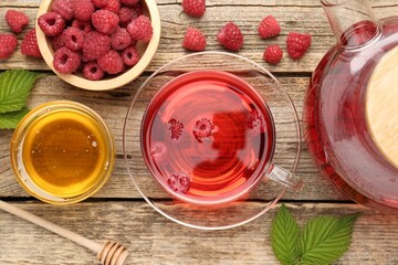 Tasty raspberry tea, berries and leaves on wooden table, flat lay