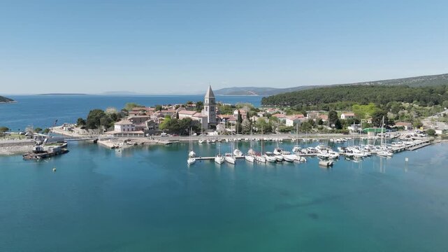 Aerial videoclip capturing sailboats passing in front of Osor Strait, showcasing scenic maritime navigation, sailing activity, and the beautiful coastal landscape from a bird's-eye perspective.