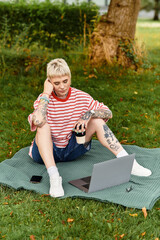 Charming young woman enjoying a sunny afternoon in the park while working on her laptop