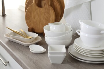 Different clean white dishware and wooden cutting boards on counter in kitchen, closeup
