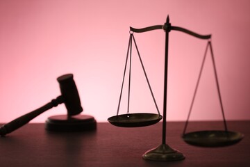 Scales of justice and judge's gavel on table against color background, selective focus