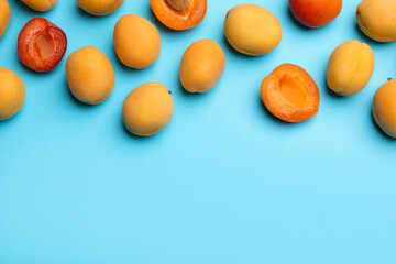 Many fresh apricots on light blue background, flat lay. Space for text