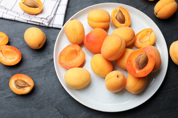Many fresh apricots on dark textured table, flat lay