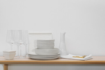 Different clean white dishware, glasses and cutlery on wooden table indoors
