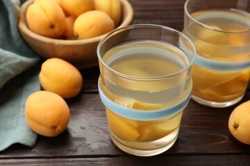 Tasty compot with apricots on wooden table, closeup