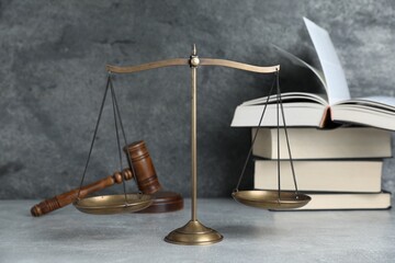 Golden scales of justice, gavel and books on grey table