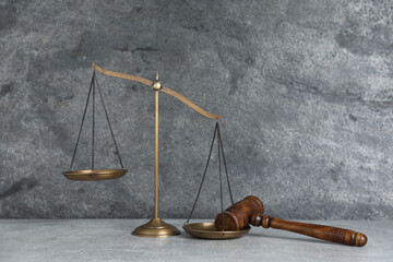 Golden scales of justice and gavel on grey table