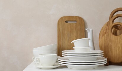 Different clean white dishware and wooden cutting boards on counter in kitchen, space for text
