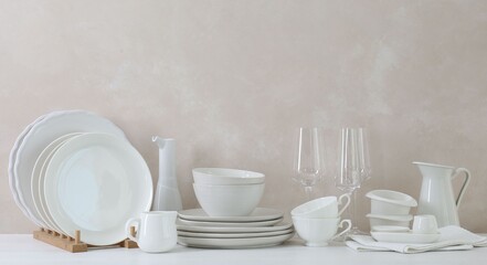 Different clean white dishware and glasses on counter in kitchen, space for text