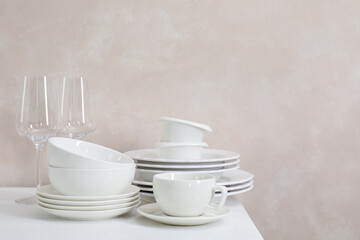 Different clean white dishware and glasses on counter in kitchen, space for text