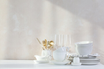 Different clean white dishware and glasses on counter in kitchen, space for text