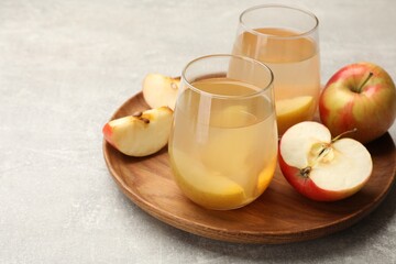 Tasty compot in glasses and fresh apples on grey table, closeup. Space for text