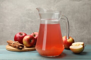 Tasty compot in glass jug, fresh apples and cinnamon on light blue wooden table