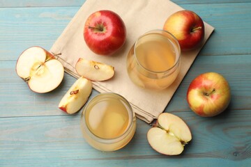 Tasty compot in glasses and fresh apples on light blue wooden table, flat lay
