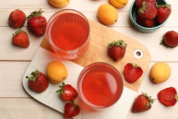Tasty compot in glasses, fresh strawberries and apricots on wooden table, flat lay