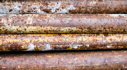 Close-up of old rusty corrugated metal surface with traces of blue paint and intense corrosion texture.
