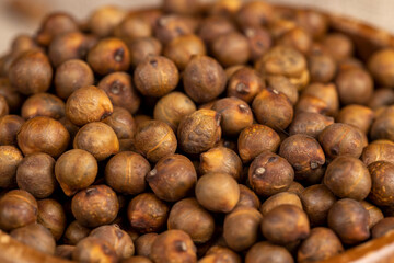 chickpeas are scattered on the table, not boiled chickpeas are on the table with a linen tablecloth, porridge is poured in a wooden bowl, closeup