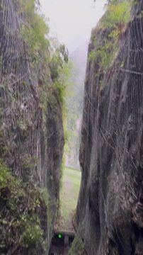 Steep wooden staircase nestled between two cliffs in the Zhangjiajie Grand Canyon, Hunan, China, surrounded by lush greenery and dramatic rock formations along the scenic hiking trail.