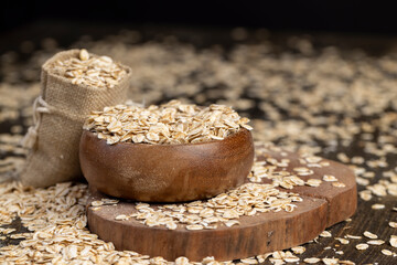 linen bag with oatmeal flakes for making porridge, scattered dry cereal flakes from oats, flattened, steamed and dried, closeup