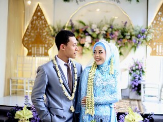 A happy newly married couple, wearing elegant blue and grey attire