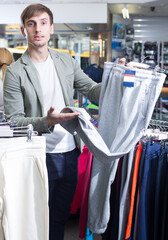 Young man shopping for sweatpants in clothing store