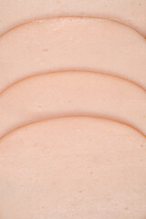 A close-up shot of several pink slices of chicken breast cold cuts, photographed from the top