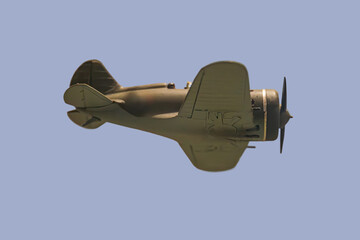 A vintage World War era aircraft flies low over water, with a camouflaged, single-engine design The...