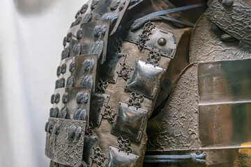 Close-up view of a Japanese armor with diagonal plate pattern, showing wear and age, riveted...