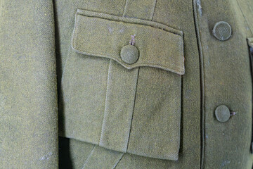 Close-up of antique military collar and sleeve, textured wool or similar fabric, muted olive green...
