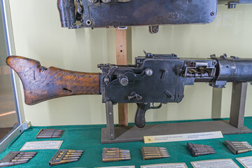 Vintage rifle wooden stock, bayonet on display in a museum setting, accompanied by ammunition...