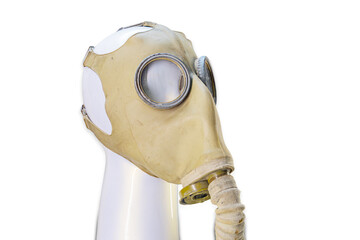 Close-up image of an antique gas mask on a white stand, with age-worn appearance yellowish-brown,...