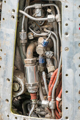 Close-up view of an open Russian jet engine, mounted on a metal frame with visible pipes, hoses,...