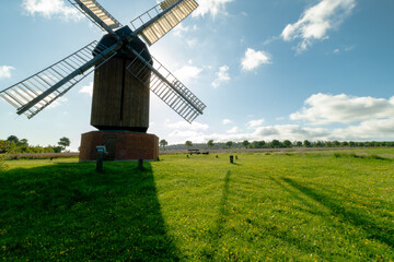 Eine weite, gepflegte Gr&uuml;nfl&auml;che erstreckt sich an der Abbenroder Bockwindm&uuml;hle. Im Bild sind der untere Teil der M&uuml;hle und zwei vollst&auml;ndige Fl&uuml;gel zu sehen, die oberen nur angeschnitten. Die Landsc