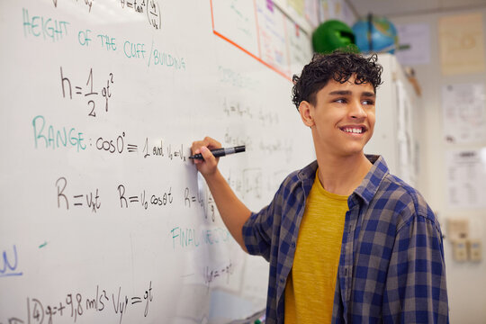 Teen high school student solving equation on whiteboard