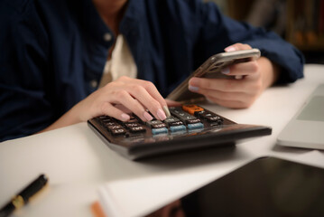 woman is calculating expenses and checking data smartphone working from home. modern financial...
