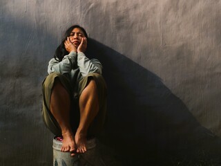 Asian sad woman sitting on gray background. Conceptual image for depression, sadness, loneliness,...