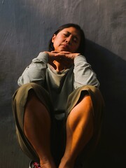 Asian sad woman sitting on gray background. Conceptual image for depression, sadness, loneliness,...