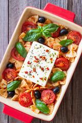 Baked feta cheese with farfalle pasta, basil, tomatoes and olives. Healthy food. Vegetarian food.