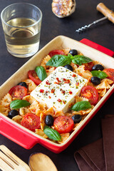 Baked feta cheese with farfalle pasta, basil, tomatoes and olives. Healthy food. Vegetarian food.