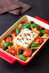 Baked feta cheese with farfalle pasta, basil, tomatoes and olives. Healthy food. Vegetarian food.