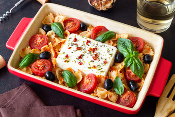 Baked feta cheese with farfalle pasta, basil, tomatoes and olives. Healthy food. Vegetarian food.