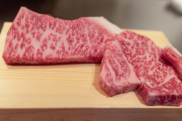 Premium Japanese A5 Kobe beef displayed on a smooth wood tray showing intricate marbling pattern...