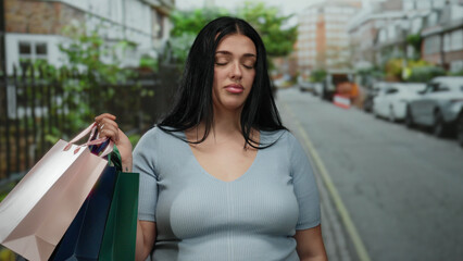 Woman shopping outdoors carrying colorful bags on a city street, expressing a thoughtful mood during an urban day.